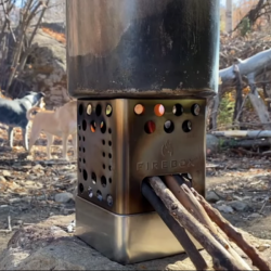 Photo of Firebox Scout Stove with sticks inside and a pot on top.